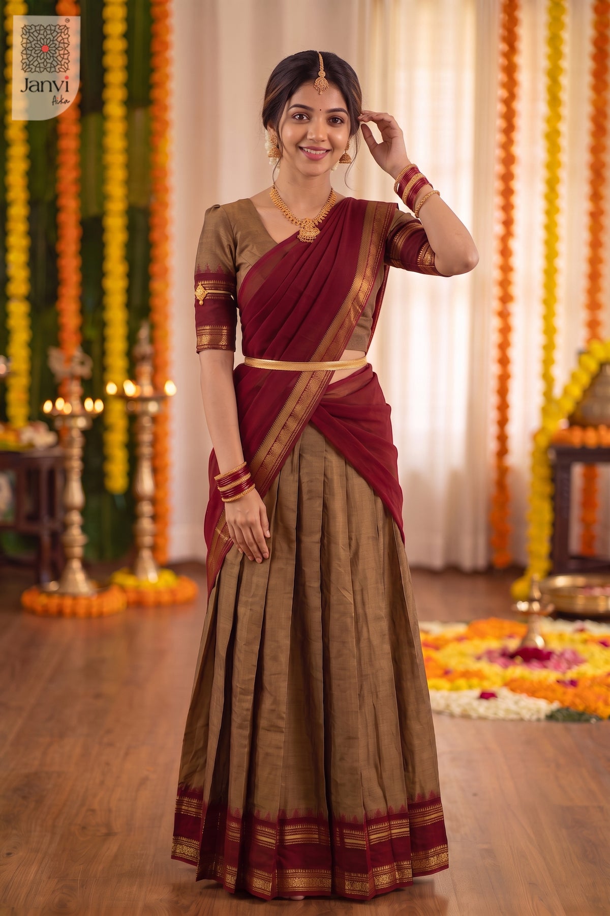 Standing pose touching hair in a festive bronze and maroon half saree lehenga attire.