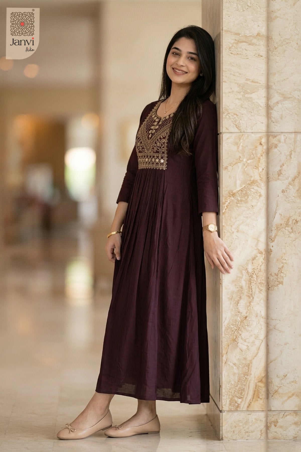 Model leaning on marble pillar in dark magenta dressy tops for women with embroidery