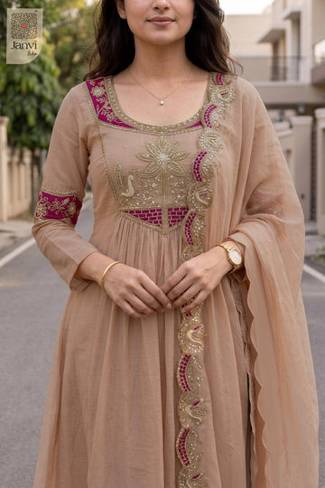 Close up view of intricate magenta zardozi work on a light peach short anarkali kurti.