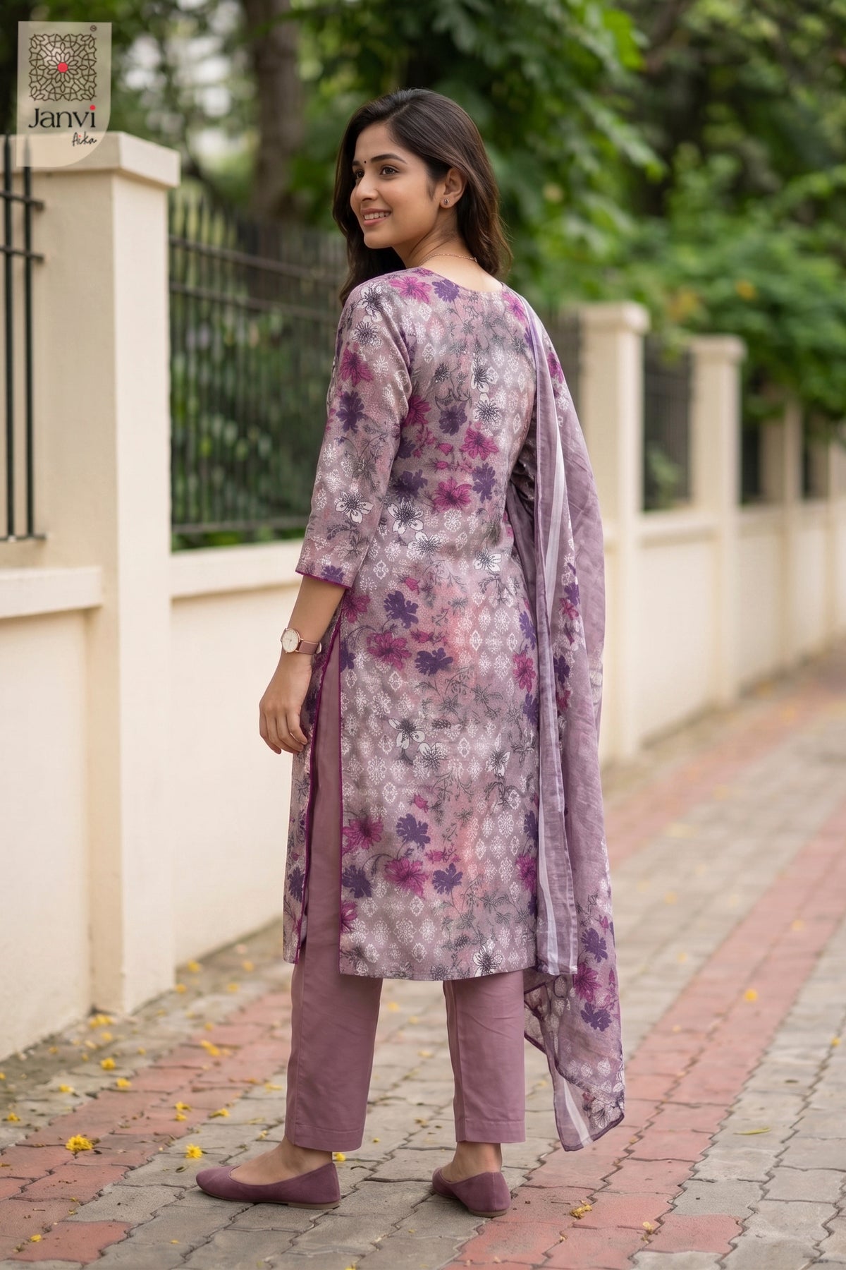 Woman wearing a floral kurta with a matching dupatta on a sidewalk.