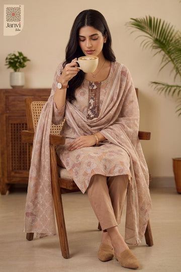 Seated indoor pose holding a tea cup wearing light peach red churidar set readymade.