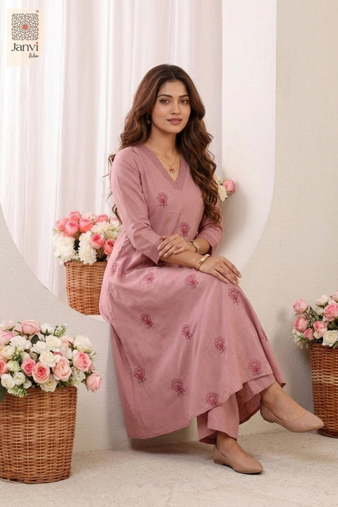 Seated studio pose next to flower basket in floral printed indo western party wear for ladies.