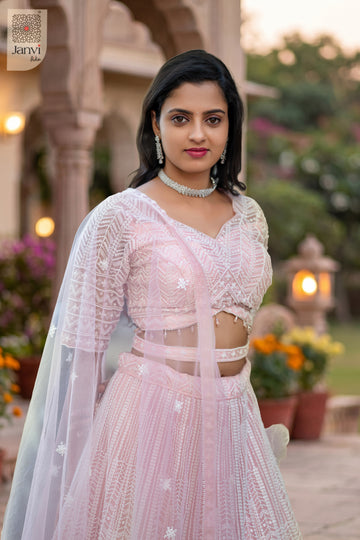 Elegant pink net wedding pink lehenga featuring a detailed waist up front smiling view.