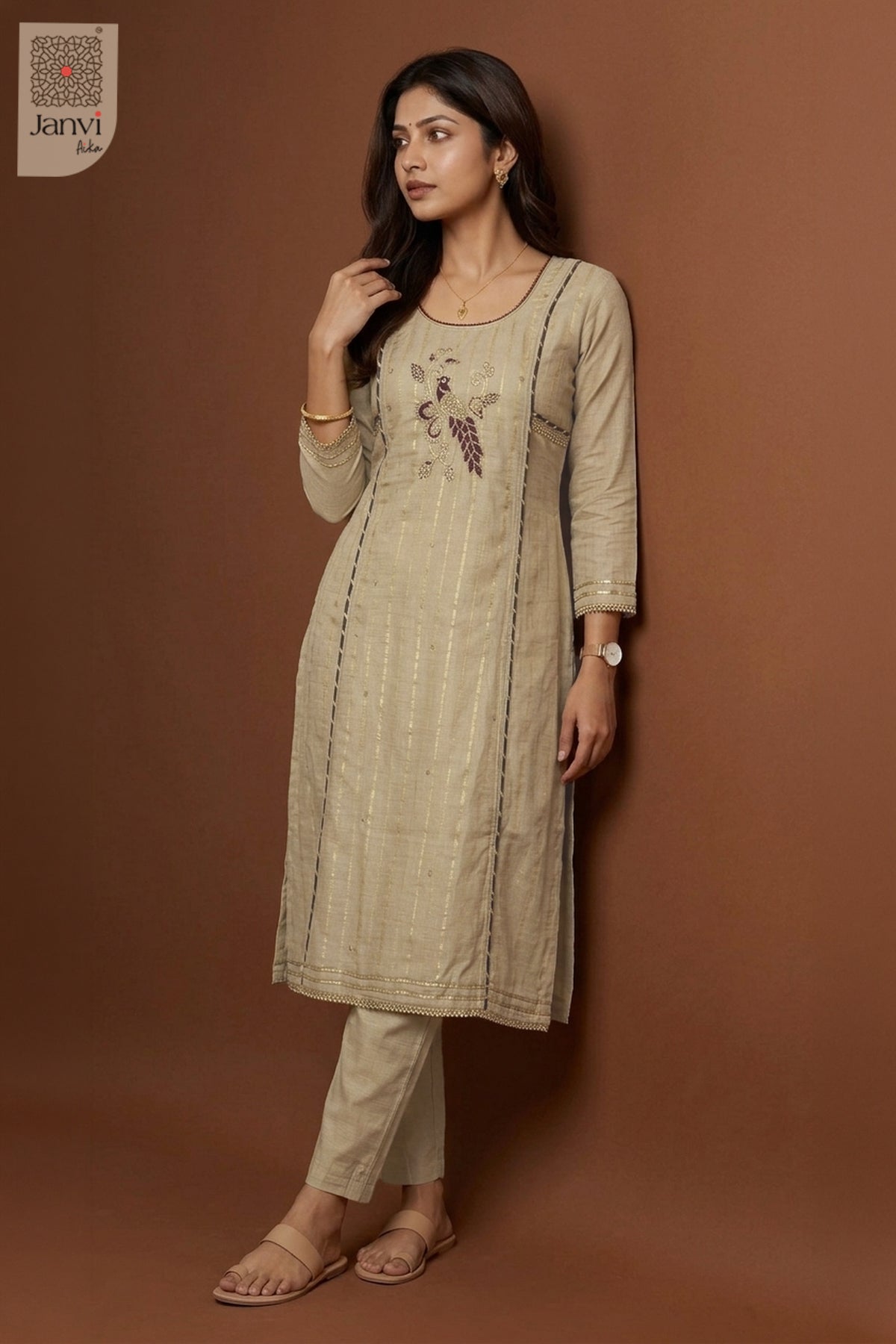 Side profile standing pose leaning on wall wearing grayish orange silk churidar set.