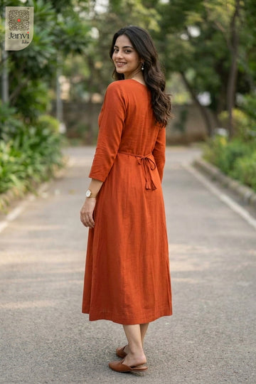 Over the shoulder rear view of model in rust dress tops for women along garden path