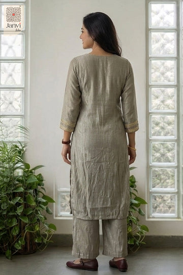 Rear view against glass block tiles in grayish blue tailored churidar sleeves kurti.