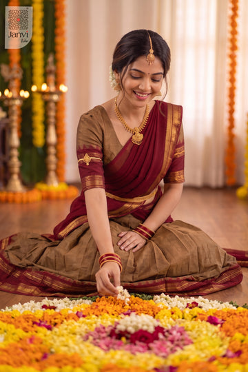 Model sitting arranging floral rangoli in a festive maroon lehenga saree ensemble.